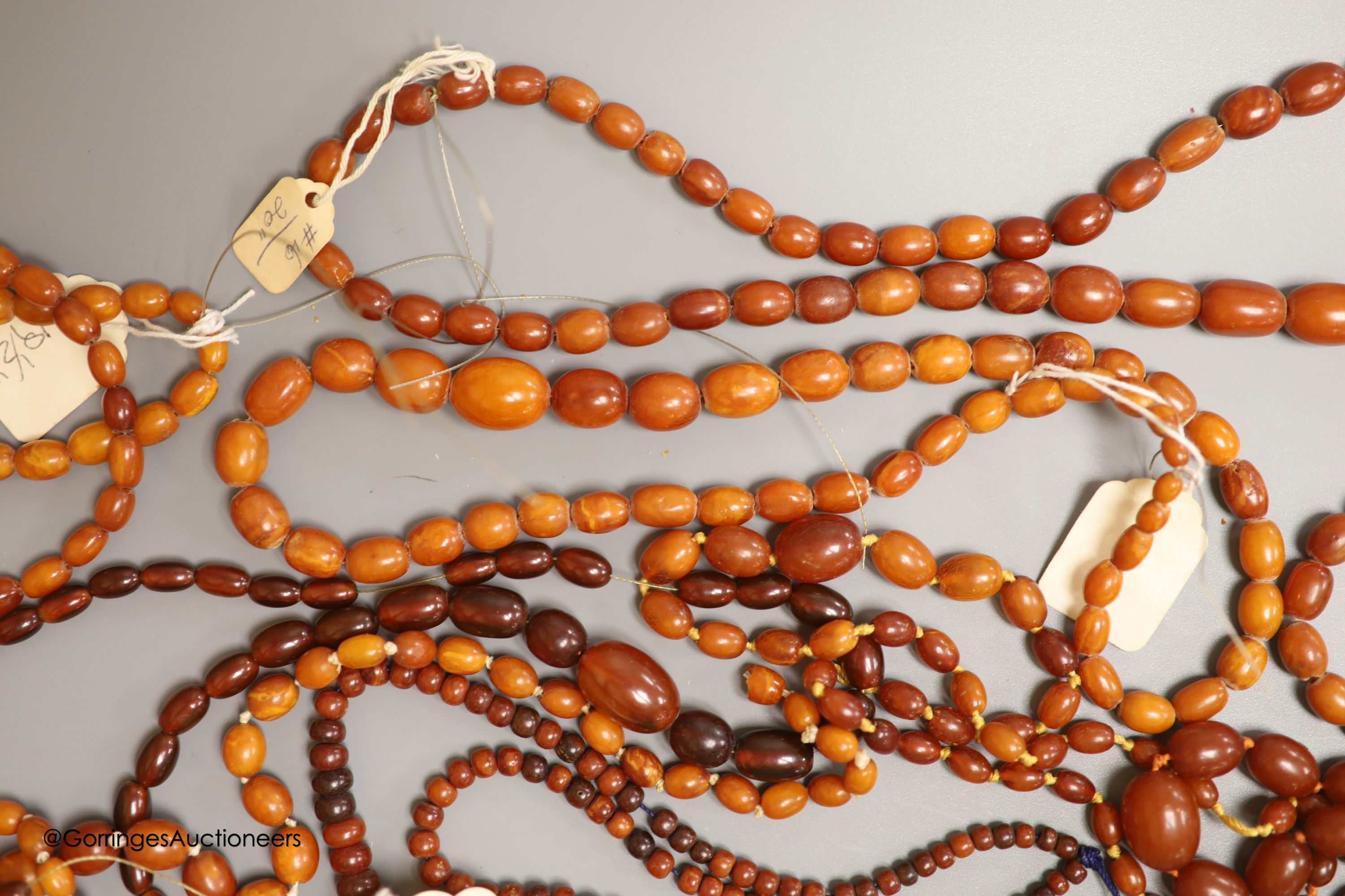 Nine assorted single strand amber bead necklaces, longest approximately 46cm, gross weight 173 grams and one simulated amber bead necklace.